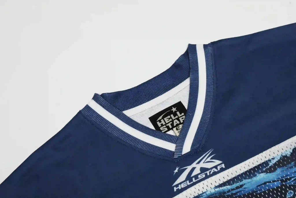 Close-up of a navy blue Hellstar jersey-style top, featuring a branded neck label and the Hellstar logo print on the chest, with white trim on the V-neckline