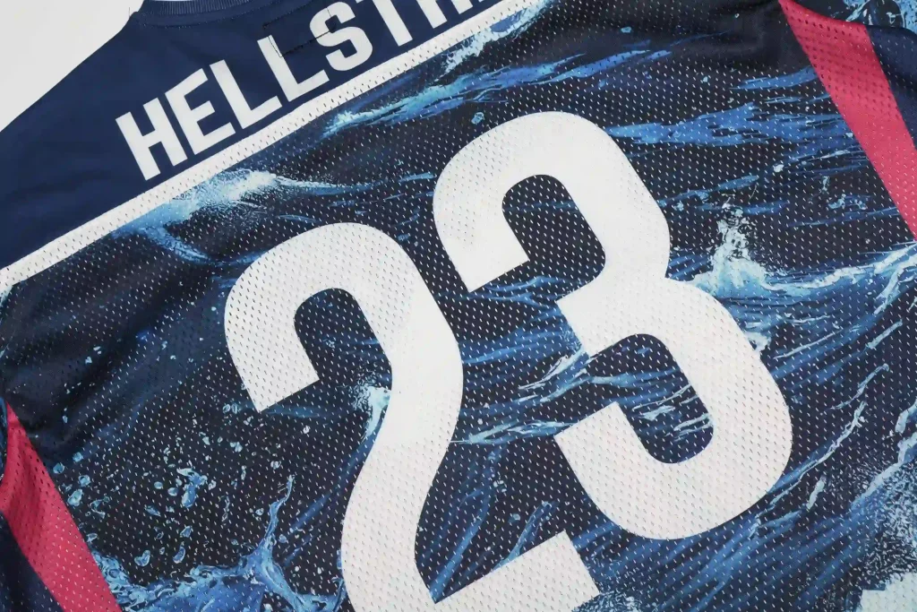 Close-up of the back of a navy blue Hellstar mesh jersey, featuring large white "23" numerals, the "HELLSTAR" text logo, and a blue water-splash graphic print on perforated mesh fabric