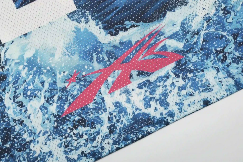 Close-up of the red Hellstar logo graphic on a mesh jersey, set against a blue water-splash print background